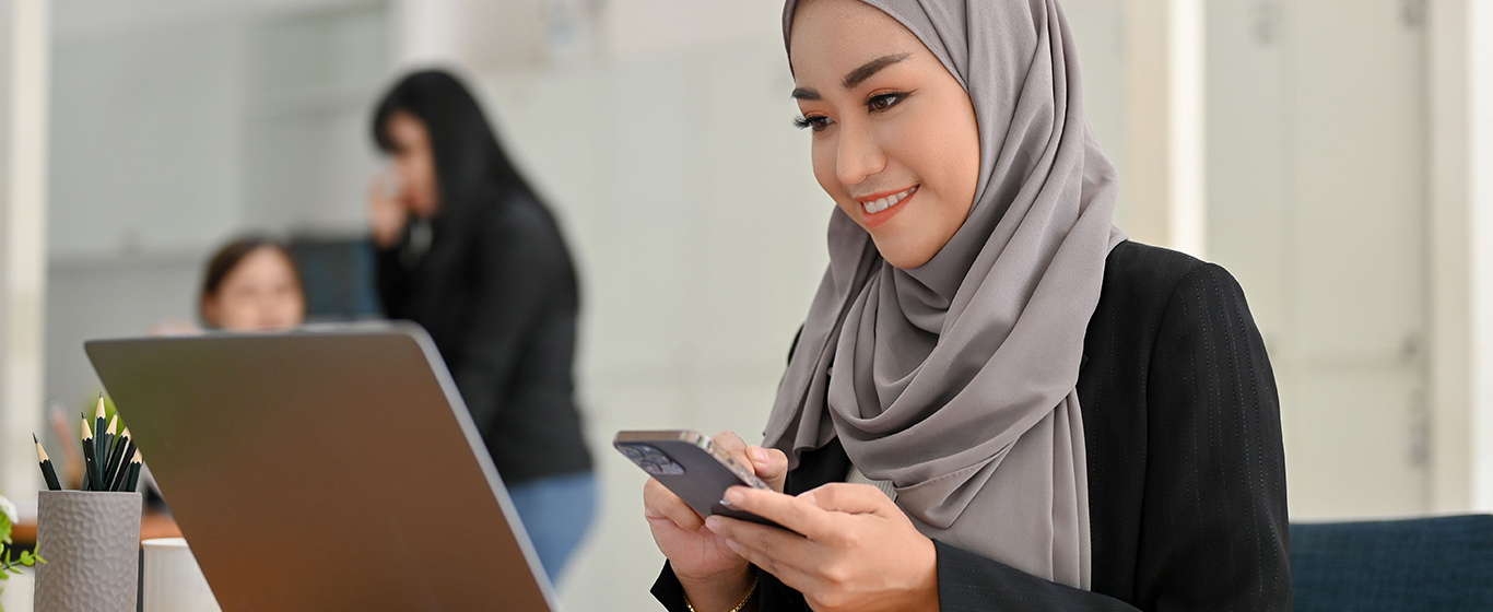wanita muslim melihat ponsel dan tersenyum