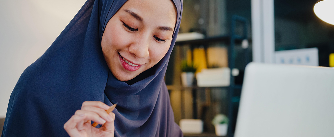 wanita muslim bekerja dengan laptop