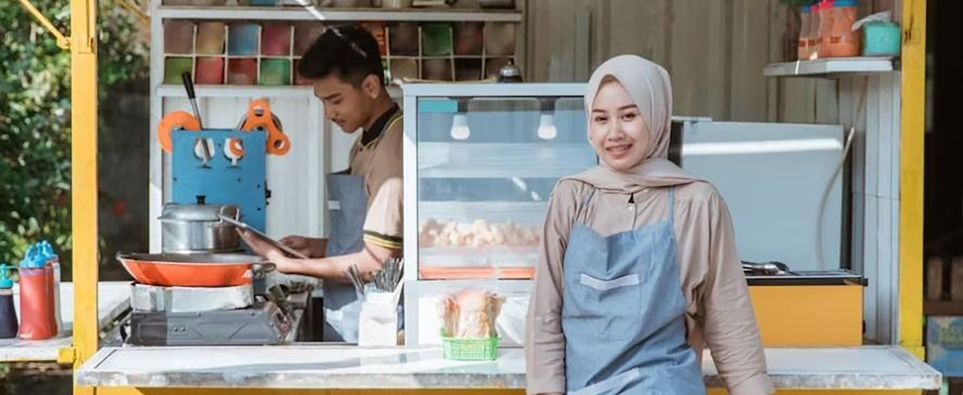 wanita berfoto di depan kedai usahanya