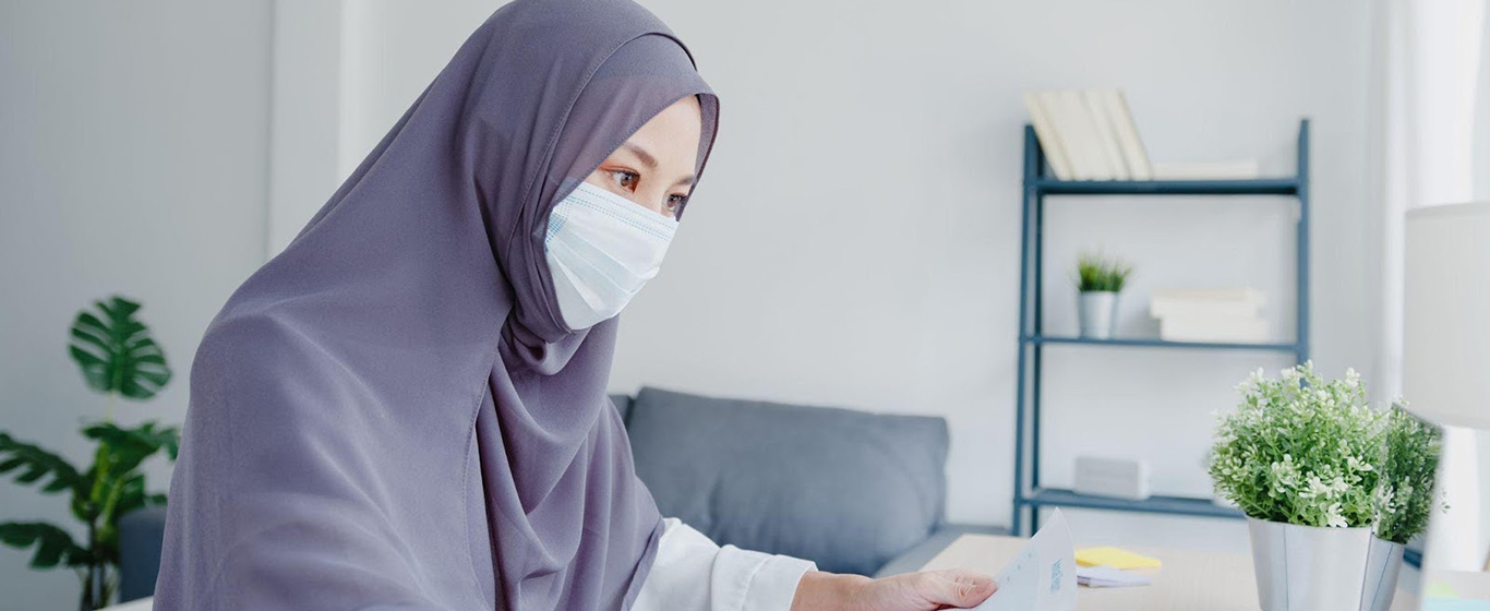 Seorang wanita berjilbab memakai masker